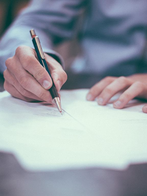 Persona firmando papeles con una pluma